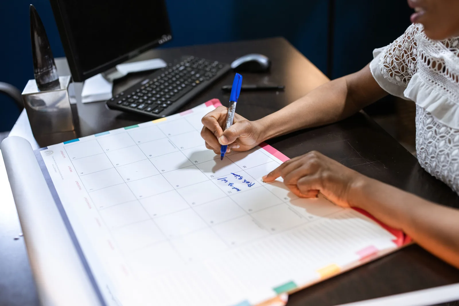 Someone writing an appointment into a desk calendar in an office